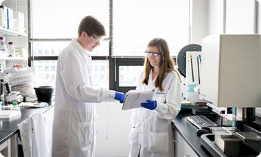 Two Arvinas scientific staffers holding conversation in front of window in lab